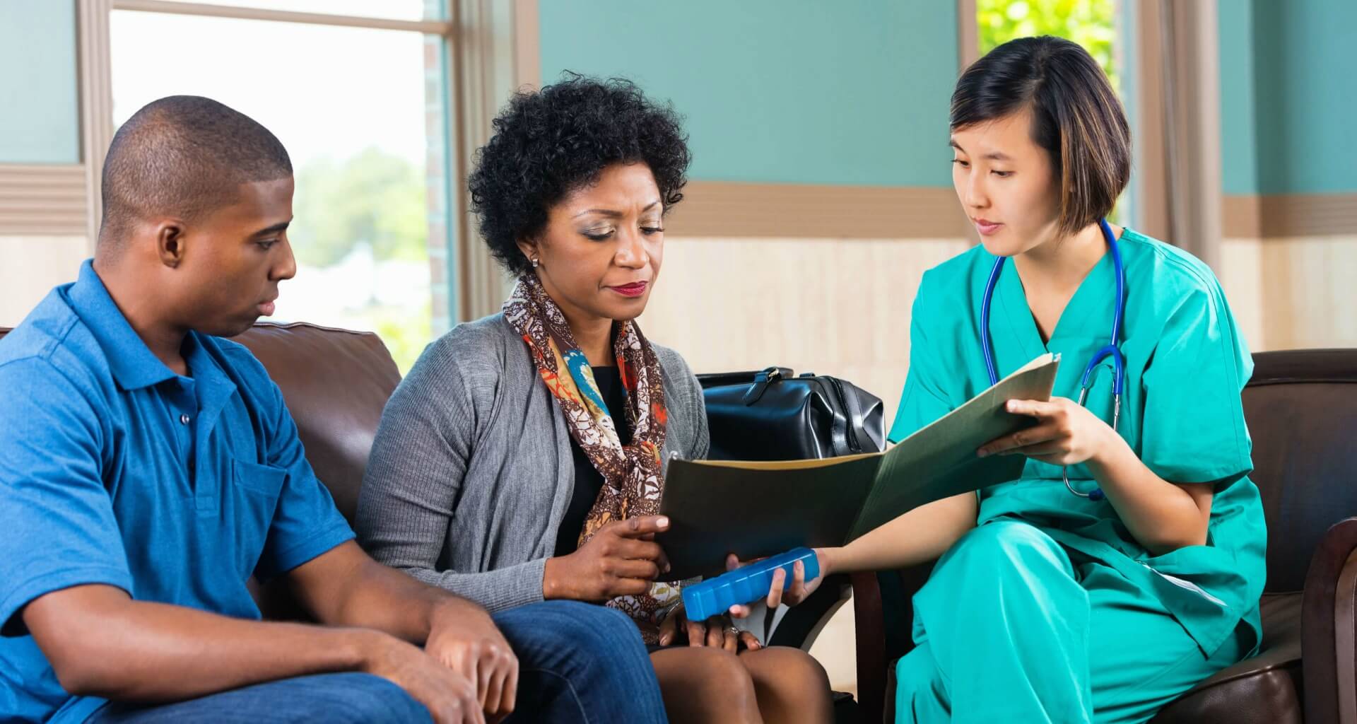 Nurse talking with older woman and son about health documents