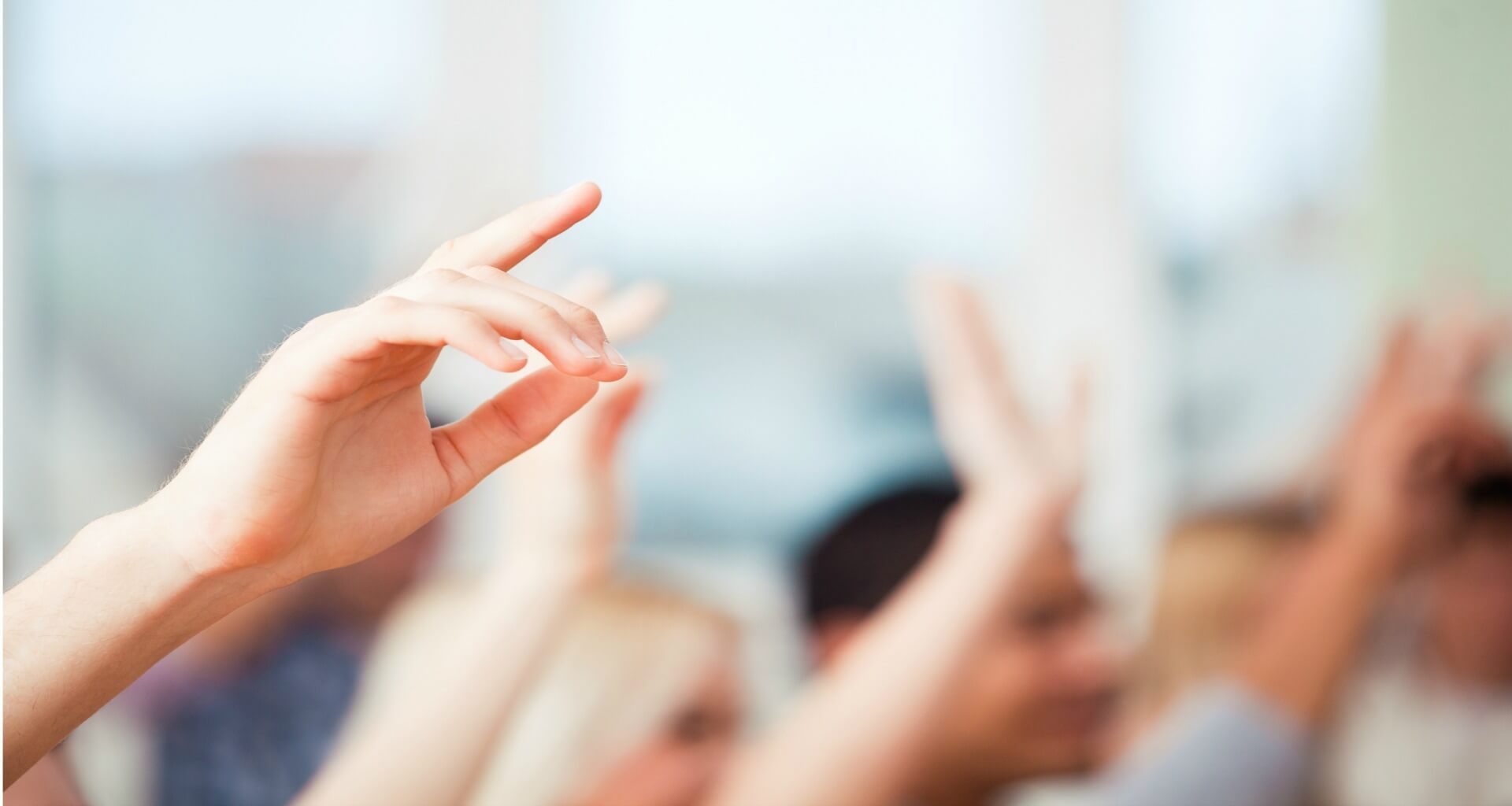 person raising their hand with a blurred background
