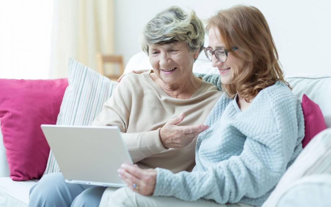 Daughter is showing old mother how to use a computer