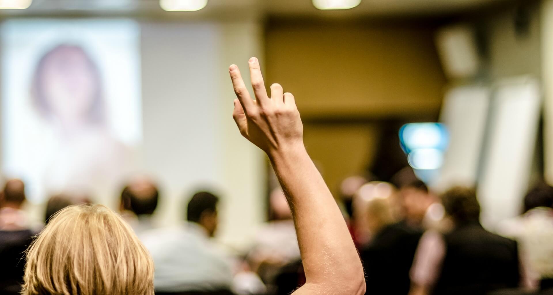 person raising their hand at a conference