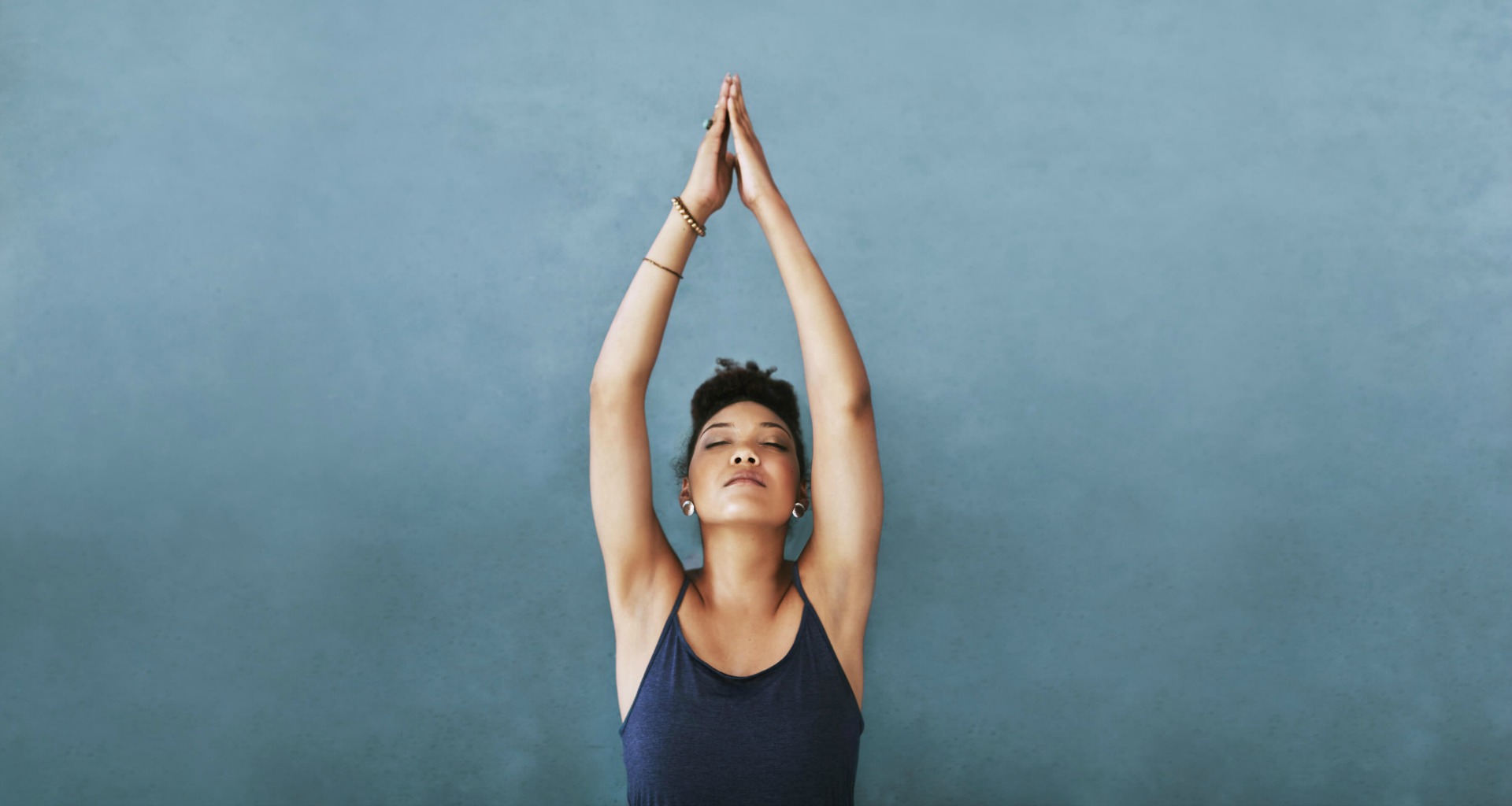 woman stretching hands overhead in yoga pose