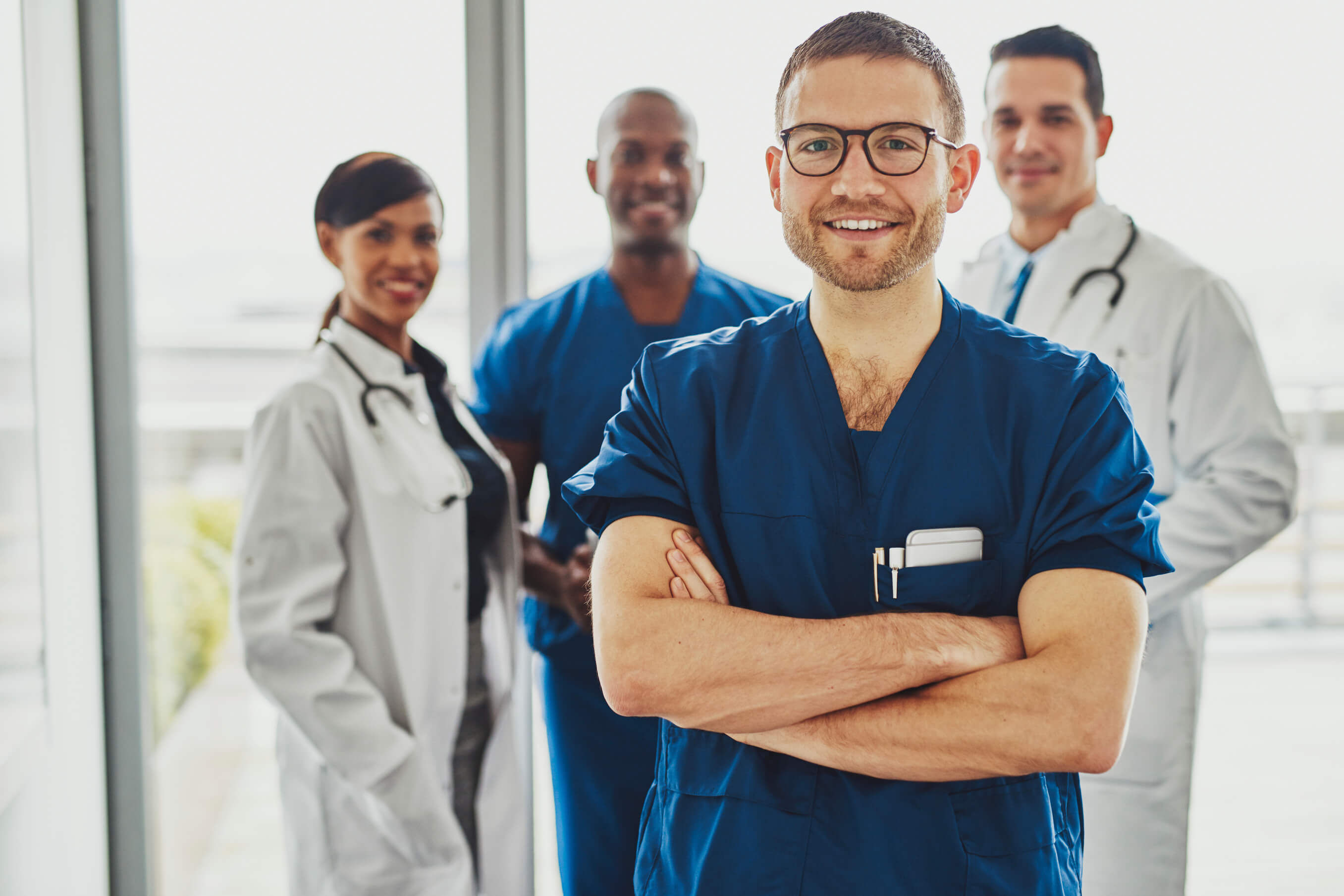 young male doctor standing in front of three other doctors