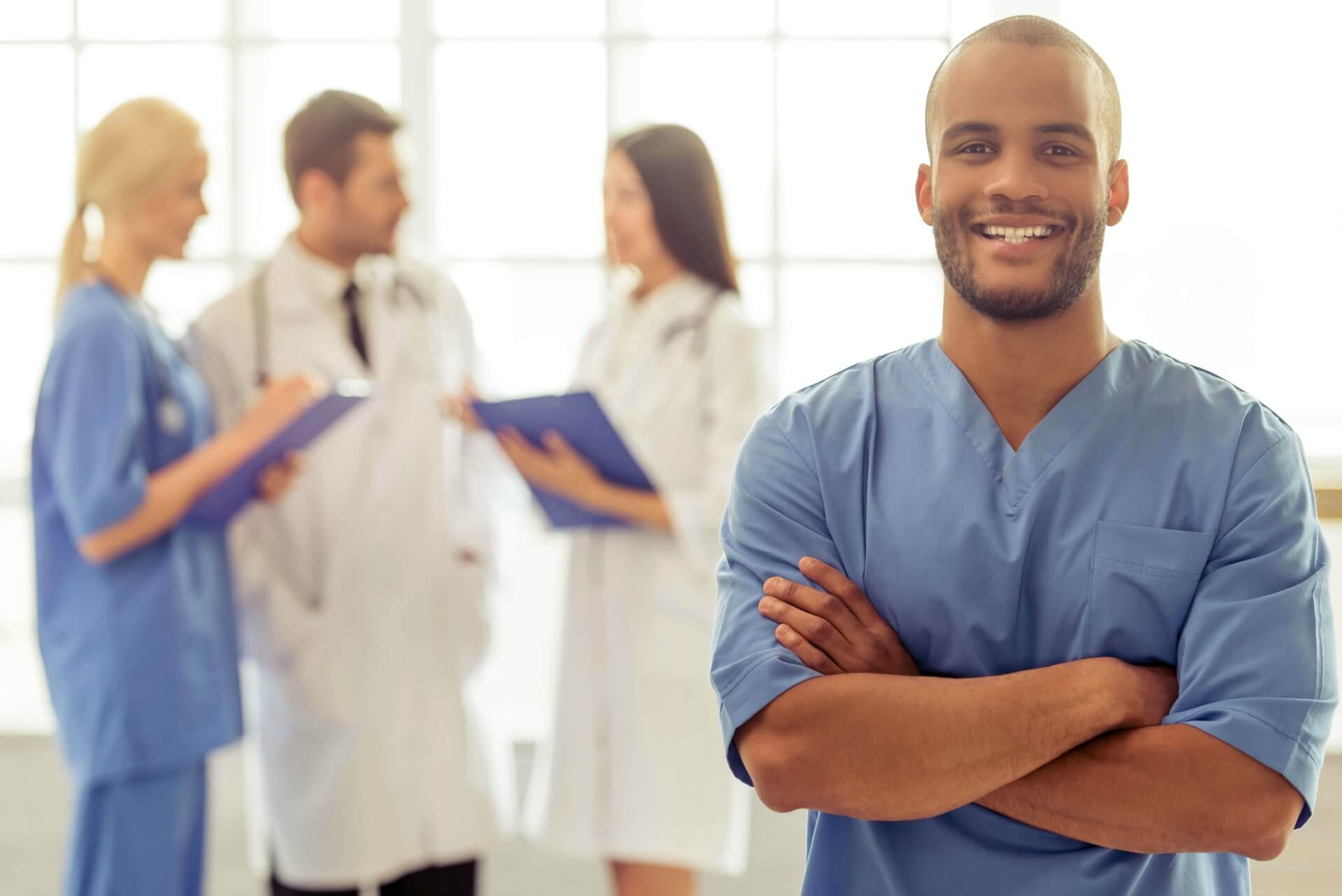 young male nurse in scrubs smiling at the camera