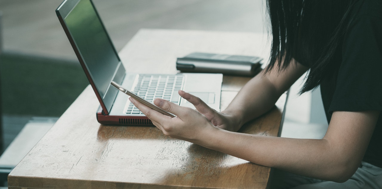 A woman on her cellphone with a laptop in the background
