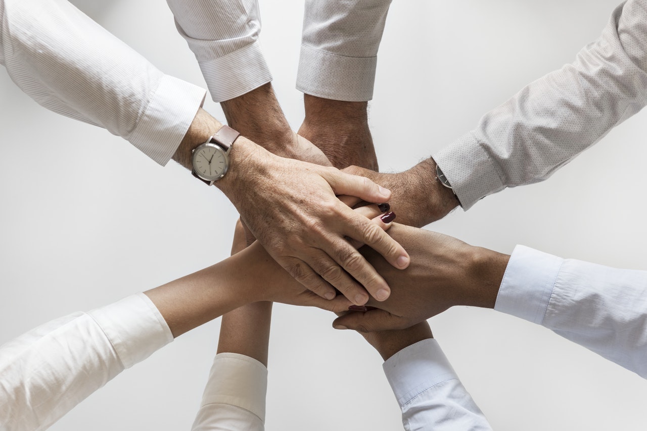 multiple people putting hands in in a circle